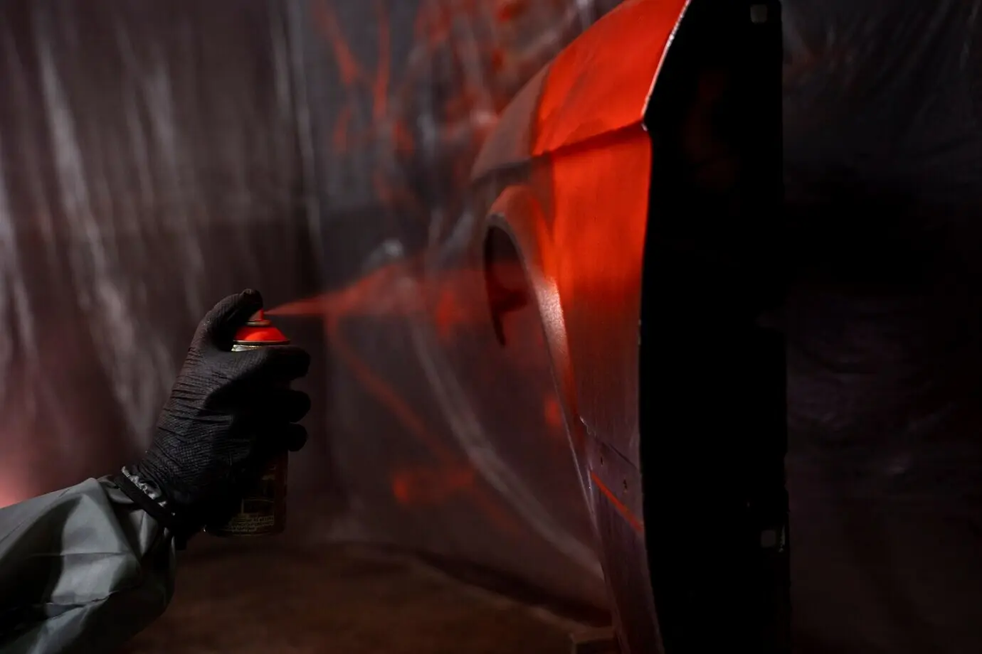 Seitenansicht: Eine Hand sprüht Pulverfarbe auf eine Tür.